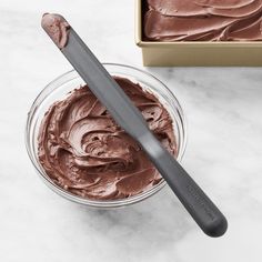 a bowl of chocolate frosting next to a spoon