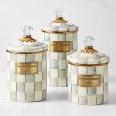 three white and gold canisters sitting on top of a table