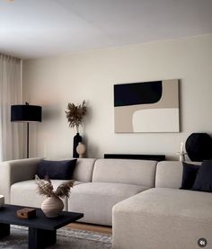 a living room with white couches and black tables in front of a large window