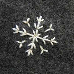 a snowflake made out of small white flowers on a black carpeted surface