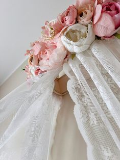 a bouquet of pink flowers sitting on top of a white lace covered bed coverlet