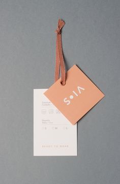 a tag with the word sona on it hanging from a brown string against a gray background