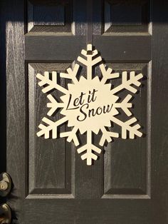 a wooden snowflake that says let it snow on the front door with bells