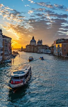 two boats are traveling down the canal at sunset