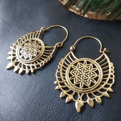 Openwork Hoop Earrings in Silver or Gold Brass. These Creoles are Elegantly Decorated with the Flower of Life Pattern Surrounded By A Circle. The Circle Of The Hoops Is Decorated With Spikes To Give These Earrings A More Ethnic Style. The Powerful Flower of Life Symbol Of Sacred Geometry Releases Good Waves. The Flower of Life Symbolizes Regeneration, Creation and Metamorphosis. She Represents the Cycle of Life. These Hoop Earrings are very elegant and they will illuminate your face. Timeless and Lightweight Creoles to Wear Everyday to Give an Ethnic Touch to Your Outfits. They are made from brass. Material: Brass Color: Silver or Gold Length: 5.7cm Width: 3.5cm Thickness: 0.2 cm Weight: 14 Gm The Pair Handmade Delivered in a Fabric Pouch Ideal for Gifting To offer or simply treat yourself Bohemian Round Brass Hoop Earrings, Small Hoop Metal Earrings For Festivals, Bohemian Teardrop Hoop Earrings With Ear Wire, Festival Dangle Metal Hoop Earrings, Festive Dangle Metal Hoop Earrings, Festival Metal Dangle Hoop Earrings, Brass Hoop Jewelry For Festivals, Bohemian Bronze Plug Earrings, Brass Dangle Hoop Earrings With Latkans