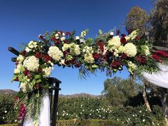 a wedding arch decorated with flowers and greenery on the side of an outdoor area