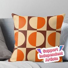 an orange and brown pillow with the words support independent artists on it, sitting on a couch