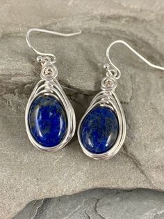 These natural Lapis Lazuli earrings are gorgeous! Lapis Lazuli stone has been valued for centuries and prized for its vibrant royal blue color. These earrings are handmade from genuine Lapis Lazuli stone. I chose to enhance this beautiful smooth stone with a woven silver wire design to let the natural beauty of the gemstone shine. The stones in each earring measure between 8-10mm. These earrings are also lightweight and perfect for daily wear. Pair these flattering earrings with your favorite ou Blue Oval Earrings With Natural Stones, Lapis Lazuli Teardrop Earrings For Gifts, Lapis Lazuli Teardrop Earrings As Gift, Teardrop Lapis Lazuli Earrings For Gift, Wire Wrapped Lapis Lazuli Dangle Earrings, Flattering Earrings, Blue Drop Earrings, Lapis Earrings, Wire Design