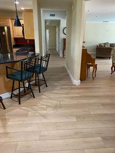 a kitchen and dining room with wood flooring in the middle, along with an open living area