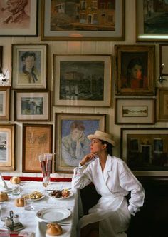 a man sitting at a table in front of a wall with pictures and food on it