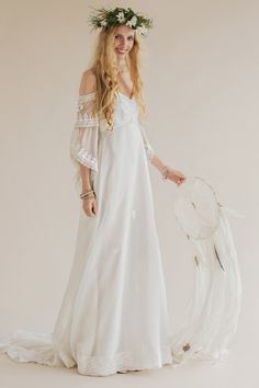 a woman wearing a white dress and flower crown standing in front of a white background