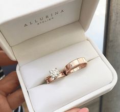 two gold wedding rings in a white box with the name aurora written on one side