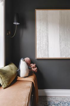 a stuffed animal sitting on top of a bed next to a framed art piece in a bedroom