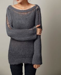 a woman wearing a gray sweater and black pants posing with her arms around her neck