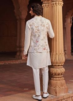 Introducing the stunning Ivory Kurta set with an Embroidered Jacket, crafted from luxurious raw silk. The ivory jacket is adorned with intricate resham, zari, zardozi, and dabka work, showcasing unique motifs that exude a regal charm. Paired with a finely detailed matching kurta and tailored pants, this outfit effortlessly combines traditional craftsmanship with contemporary design. Ideal for Haldi, Mehndi, Sangeet, or as wedding guest attire, it embodies sophistication and cultural richness, making it a timeless addition to any wardrobe. Composition : Jacket, Kurta and Pants - Raw SilkCare: Dry Clean Only and Vacuum Storage Delivery : 4-6 weeks as the product is hand crafted. Check Size Guide or choose MySize for free customisation (All Sizes above XL can be made at 15% additional cost) F Off White Raw Silk Set With Intricate Embroidery, Cream Bandhgala With Chikankari Embroidery In Raw Silk, Silk Nehru Jacket With Intricate Embroidery For Festive Occasions, White Embroidered Semi-stitched Nehru Jacket, Off White Nehru Jacket With Zari Work, Festive Silk Nehru Jacket With Intricate Embroidery, Designer Cream Embroidered Bandhgala, Silk Nehru Jacket With Intricate Embroidery For Eid, Off White Bandhgala With Intricate Embroidery For Designer Wear