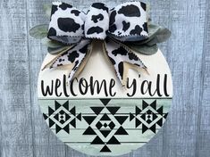 a welcome yall door hanger with a cow print bow