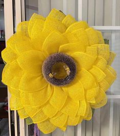 a large yellow flower hanging from the side of a window