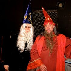 two men dressed up as wizard and witch with long white hair, wearing red robes