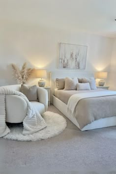 a large white bed sitting inside of a bedroom next to two lamps on either side of the bed