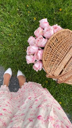 a woman sitting on the grass with pink roses in her lap and wearing white shoes