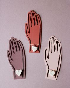 three hand shaped magnets with hearts attached to them