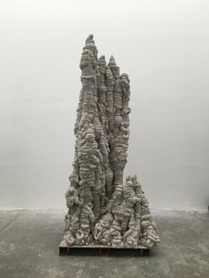 a sculpture made out of rocks sitting on top of a wooden pallet in front of a white wall