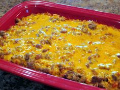 a red casserole dish filled with meat and cheese