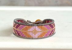 a pink and orange beaded bracelet sitting on top of a white counter next to a window