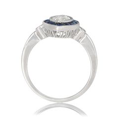 This is an antique Sapphire-Halo ring featuring a very rare marquise 1.01 Carat diamond in the center. The sapphire halo around the diamond consists of natural calibre French-cut sapphires with a total carat weight of .50. The diamond is GIA certified. ✦DIAMOND SPECIFICATIONS: Center Diamond Weight: 1.01 Carats Center Diamond Clarity: VS2 Clarity Center Diamond Color: H Color ✦ ENGAGEMENT RING SPECIFICATIONS: Ring Material: Handcrafted Platinum Total Gram Weight: 5.0g Ring Material: Platinum ✦ W Oval Platinum Diamond Ring Gia Certified, Gia Certified Oval Platinum Ring, Gia Certified Oval Platinum Cluster Ring, Gia Certified Art Deco Rings, Anniversary Asscher Cut Halo Ring With Center Stone, Anniversary Halo Ring With Asscher Cut Center Stone, Platinum Sapphire Ring With Vvs Clarity, Art Deco Gia Certified Round Cut Sapphire Ring, Classic Bezel Set Cluster Promise Ring