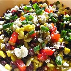 a colorful salad with corn, black beans, carrots and feta cheese on top