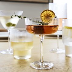 three glasses filled with different types of drinks on a table next to each other and one has an orange slice in it