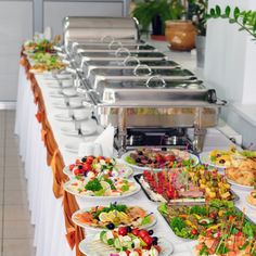 a buffet table filled with lots of different types of food on plates and serving utensils