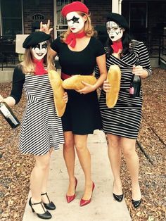 three women dressed up in costumes and holding hotdogs with faces painted on them