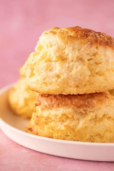 two biscuits stacked on top of each other in a white plate with pink background and text overlay