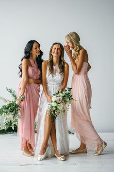 three bridesmaids pose for a photo with their bouquets in front of them