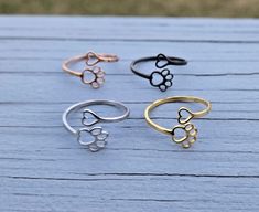 This is a really cute, adjustable stainless steel ring. It has a paw print on one side and a heart on the other. You can choose from 4 colors: silver, gold, black, or rose gold.  I would say this is adjustable from a size 6 to a size 10. Each item will be sent to you in a gift bag or box. This is perfect for anyone! Birthdays, anniversaries, jewelry for bridesmaids, gifts for Mom, or any other occasion. Please contact me if you have any custom requests or questions. Shipping is typically 4 to 6 Color Gifts, Paw Print Ring, Rose Noir, Birthday Mom, Stainless Steel Rings, Steel Ring, Bridesmaids Gifts, Rings Statement, Gold Rose