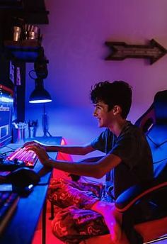 a young man sitting in front of a computer at a desk with a keyboard and mouse