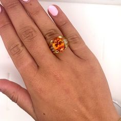 GIA Certified Unisex Ring in 18K Yellow Gold, weighing 14.90 grams, boasting a 13.5 carat oval cut Spessartine Garnet center stone. The vibrant orange gem is superbly clean and lustrous. Exploding with color and brilliance. Adorned with 16 princess cut diamond side stones, totaling 0.96 carats.  This Spessartine Garnet is extremely rare due to its rich Mandarine Orange color, lack of inclusions, and 13.5 carat size.   Item Details: - Type: Unisex Ring  - Metal: 18K Yellow Gold  - Weight: 14.90 Grams  - Setting: 4-Prong  - Size: 7.5 (adjustable) - Mounting: 17 MM elevation  ___________________________  Center Stone Details: - Type: Spessartine Garnet  - Carat: 13.5  - Cut: Oval-Brilliant - Color: Mandarine Orange  - Measurements: 14.24 x 10.75 x 8.08 MM   GIA Certificate #: 6234022072  GIA Luxury Orange Gemstone Ring, Luxury Orange Gemstone Accented Jewelry, Luxury Orange Jewelry With Gemstone Accents, Luxury Orange Gemstone Jewelry, Orange Oval Cabochon Jewelry For Formal Occasions, Formal Orange Oval Cabochon Jewelry, Formal Orange Oval Rings, Orange Topaz Ring With Center Stone As Gift, Orange Topaz Ring With Center Stone For Gift