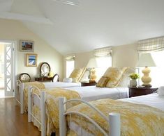 two beds in a room with yellow comforters and white bedding, one has a mirror on the wall