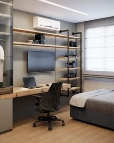 a bedroom with a bed, desk and computer monitor on the wall next to it