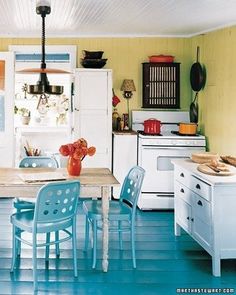 a kitchen filled with lots of white appliances and blue flooring next to a dining room table