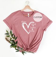 TITLE: Custom Mama Shirt, Personalized Mom Shirt, Mom Heart Shirt, Mom Shirt with Kids Names, Gift for Mom, Mom Gift Shirt, Mother's Day Gift Shirt → All our simple color ones like White and Black are 100% Cotton. → All our Heathered Colors are cotton/polyester blend and they are super comfy soft! → Bella-Canvas Unisex Jersey Short Sleeve Crew-Neck Unisex T-Shirt → Soft and High-Quality Fabric → Sueded Jersey → Pre-shrunk → Taped shoulder-to-shoulder → Tear away label → Side Seamed → Retail fit Cotton Tops With Heart Print For Mother's Day, Mother's Day Crew Neck Top With Heart Graphic, Casual Tops With Heart Shape And Name Print, Casual Heart-shaped Top With Name Print, Short Sleeve Shirt With Heart Graphic For Mother's Day, Short Sleeve Top With Heart Graphic For Mother's Day, Valentine's Day Short Sleeve Tops With Name Print, Kids Names, Heart Shirt