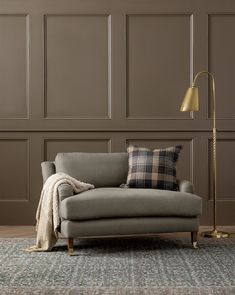 a living room with a couch, lamp and rug on the floor in front of a wall