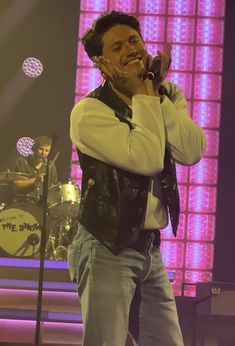 a man standing on top of a stage holding his hands up to his face while singing