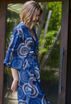 Eco friendly caftans and tunics inspired by the ocean, made on main street. Ethically sourced and locally made in Los Angeles. When we travel, we want clothes that take up minimum space but do maximum work. Meet the Kimono Wrap Duster. It's a dress. It's a duster. It's a robe. It's a cover-up. This one does it all and we couldn't be happier! As a dress, two discreet buttons keep the wrap securely in place and give the dress an architectural drape. The removable self-tie belt can be added for shape and definition. As a duster or cover-up, the flowing fabric and wide sleeves are instant chic. Wear it to dinner, layer it over jeans and a tee for a meeting, toss it over a bathing suit, the possibilities are endless. The delicate circles on this Matahari print remind us of coral reefs and endle Blue Tunic With Kimono Sleeves For Vacation, Blue Tunic With Kimono Sleeves For Summer, Relaxed Fit Tunic With Kimono Sleeves, Blue Tunic With Kimono Sleeves, Printed Long Sleeve Kaftan For Beach Cover-up, Blue V-neck Kimono For Loungewear, Floral Print V-neck Kaftan For Beach Cover-up, Printed Maxi-length Kimono For Beach, Printed V-neck Kaftan Beachwear