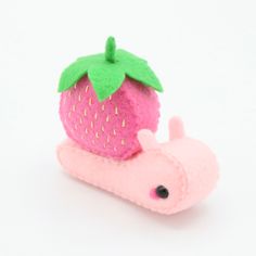 a pink toy with a strawberry on top of it's back end and a green leaf