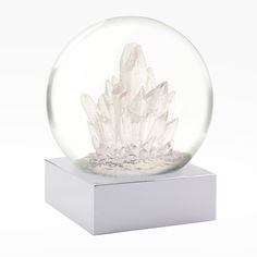 a clear crystal ball with white crystals inside on a white stand against a white background