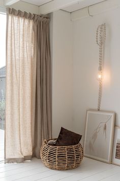 a wicker basket sitting on the floor next to a window in a white room