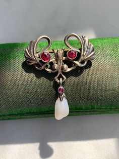 Marked: 800 (800 Silver), MO or OM? (maker's mark) Height: 1.20 inches Length: 0.98 inches Weight: 4.15 grams Features a pearl, red stones have not been tested Looks like a stylized Ginkgo Leaf, floral details, suspending a pearl Condition: Some light wear. Some extra glue on the pearl. Red Brooch Jewelry For Formal Occasions, Antique Red Brooch, Antique Red Brooch Jewelry, Victorian Jeweled Brooches As Gift, Antique Red Brooch For Formal Occasions, Antique Jeweled Brooches As Gift, Ornate Red Jewelry Brooch, Antique Red Brooch As Gift, Antique Red Brooches As Gift