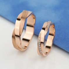 two rose gold wedding rings with diamonds on the inside, sitting next to each other